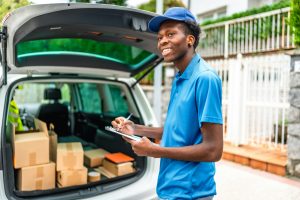 African delivery man verifying the packages on a van